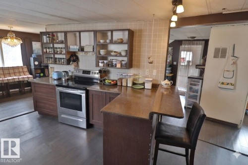 The kitchen features dark wood cabinetry, a stainless steel range, and a tiled backsplash - 11 Willow Park Estates, Leduc, AB - Indoor Photo Showing Kitchen