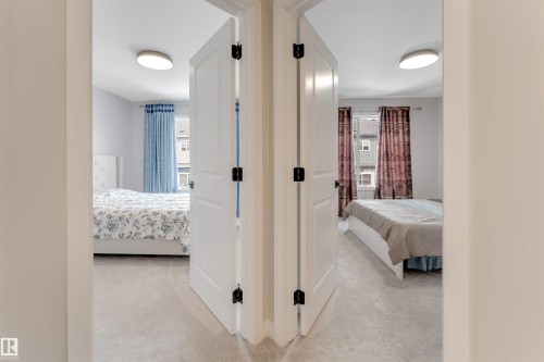 Two separate rooms, each featuring a window with curtains and a ceiling-mounted light fixture, are visible from a central hallway with light-colored carpeting - 6404 27 Avenue, Edmonton, AB - Indoor Photo Showing Other Room