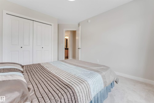 The room features light-colored walls and carpeting, a closet with white bi-fold doors, and a doorway leading to a room with a vanity - 6404 27 Avenue, Edmonton, AB - Indoor Photo Showing Bedroom
