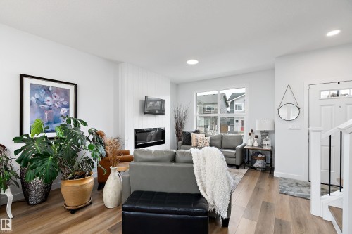 Living area featuring light wood flooring, an electric fireplace with a white shiplap wall, and large windows providing natural light - 20 Hemingway Crescent, Spruce Grove, AB - Indoor Photo Showing Other Room With Fireplace