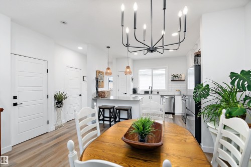 The dining area features an oval wood table with a black chandelier overhead - 20 Hemingway Crescent, Spruce Grove, AB - Indoor Photo Showing Dining Room
