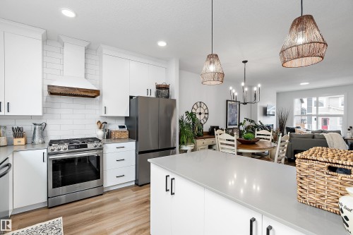 Modern kitchen featuring white cabinetry, stainless steel appliances, light-colored countertops, and hardwood flooring - 20 Hemingway Crescent, Spruce Grove, AB - Indoor Photo Showing Kitchen With Upgraded Kitchen