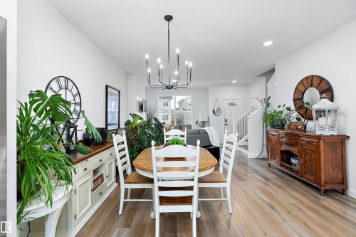 The property features an open-concept living area with light-toned flooring, a dining area with an oval table and white chairs, and a chandelier - 20 Hemingway Crescent, Spruce Grove, AB - Indoor Photo Showing Dining Room