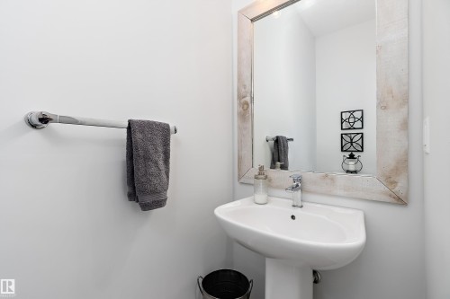 Bathroom featuring a pedestal sink, a chrome faucet, and a mirror with a rustic-style wooden frame - 20 Hemingway Crescent, Spruce Grove, AB - Indoor Photo Showing Bathroom