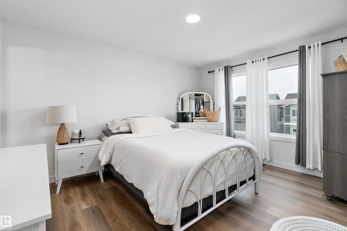 This room features hardwood style flooring, recessed lighting, and windows with white trim - 20 Hemingway Crescent, Spruce Grove, AB - Indoor Photo Showing Bedroom
