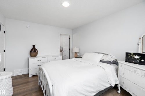 Bedroom featuring hardwood style flooring, light-colored walls, and a white door with black hardware - 20 Hemingway Crescent, Spruce Grove, AB - Indoor Photo Showing Bedroom