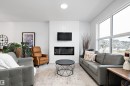 The living room features a fireplace with a white shiplap-style surround, large windows, and an overhead circular light fixture - 20 Hemingway Crescent, Spruce Grove, AB  - Indoor Photo Showing Living Room With Fireplace 