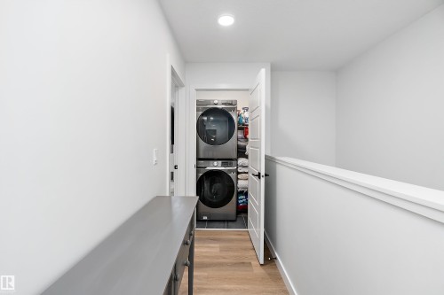 Laundry area featuring stacked appliances and wood-look flooring - 20 Hemingway Crescent, Spruce Grove, AB - Indoor