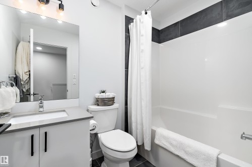 Bathroom featuring a vanity with a rectangular sink, a toilet, and a shower-tub combination with a white shower curtain - 20 Hemingway Crescent, Spruce Grove, AB - Indoor Photo Showing Bathroom