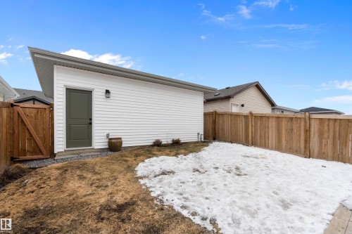 The property features a white exterior, a durable wooden fence, and a convenient side door - 20 Hemingway Crescent, Spruce Grove, AB - Outdoor With Exterior