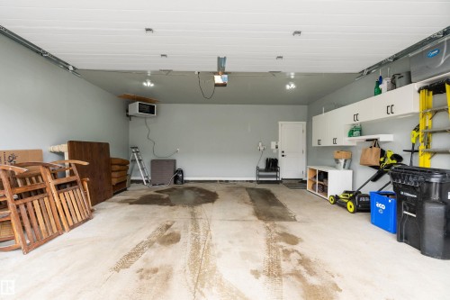 Spacious garage featuring light gray walls, a concrete floor, and white overhead storage cabinets - 20 Hemingway Crescent, Spruce Grove, AB - Indoor Photo Showing Garage