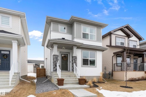 The property features a contemporary exterior with white siding, grey stone accents on the porch pillars, and a dark grey front door - 20 Hemingway Crescent, Spruce Grove, AB - Outdoor With Facade