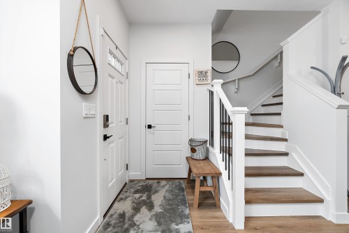 The entry features a white door with a window, a light-colored rug, and a staircase with wood treads and a white railing with black balusters - 20 Hemingway Crescent, Spruce Grove, AB - Indoor Photo Showing Other Room