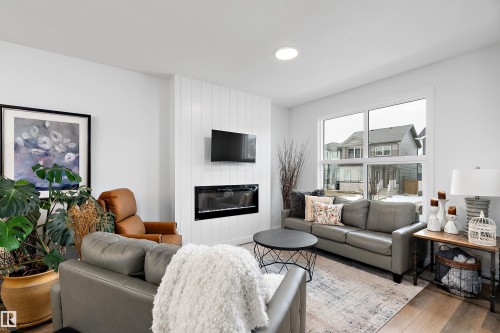The living room features an electric fireplace with a shiplap accent wall, recessed lighting, and large windows providing natural light - 20 Hemingway Crescent, Spruce Grove, AB - Indoor Photo Showing Living Room With Fireplace