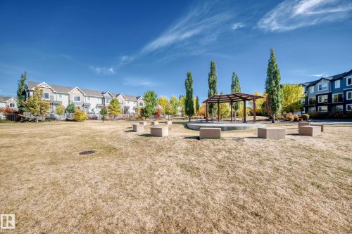 Expansive community greenspace featuring a gazebo and permanent seating, with residential properties visible in the background - 63 3625 144 Avenue Nw, Edmonton, AB - Outdoor