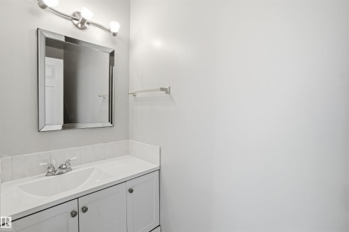 Bathroom vanity featuring a white countertop with an integrated sink, chrome faucet, and white cabinetry - 18297 74 Avenue, Edmonton, AB - Indoor Photo Showing Bathroom