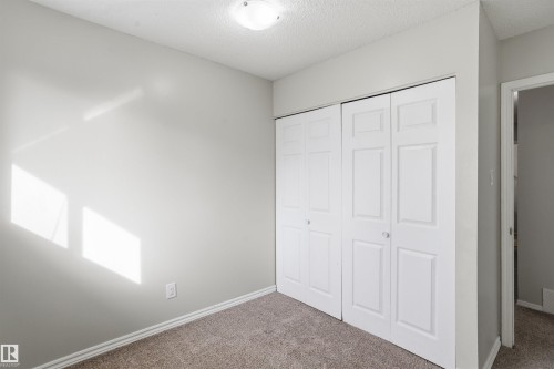 Room featuring light gray walls, carpet flooring, and white bi-fold closet doors - 18297 74 Avenue, Edmonton, AB - Indoor Photo Showing Other Room