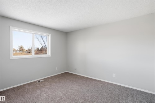 This room features light grey walls, a window with a white frame, and grey carpeting - 18297 74 Avenue, Edmonton, AB - Indoor Photo Showing Other Room