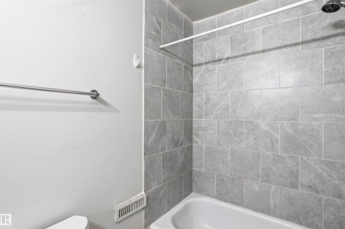 The bathroom features a tiled shower with a white bathtub and a shower head - 18297 74 Avenue, Edmonton, AB - Indoor Photo Showing Bathroom