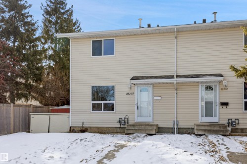 The property features a two-story exterior with light-colored siding and a front entrance with a white door - 18297 74 Avenue, Edmonton, AB - Outdoor