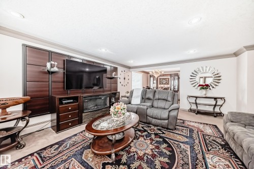 Living area featuring crown molding, recessed lighting, and an entertainment wall with an electric fireplace - 12131 101 Street Nw, Edmonton, AB - Indoor Photo Showing Living Room