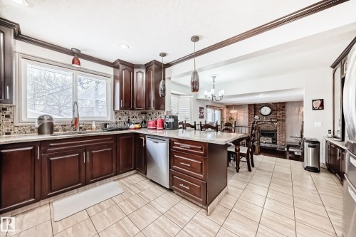 Well-appointed kitchen featuring dark wood cabinetry, granite countertops, and stainless steel appliances - 12131 101 Street Nw, Edmonton, AB - Indoor Photo Showing Kitchen With Upgraded Kitchen