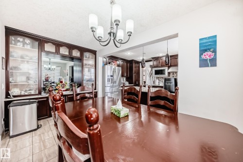 Dining area featuring a dark wood dining table and chairs, tiled flooring, and a chandelier with five lights - 12131 101 Street Nw, Edmonton, AB - Indoor