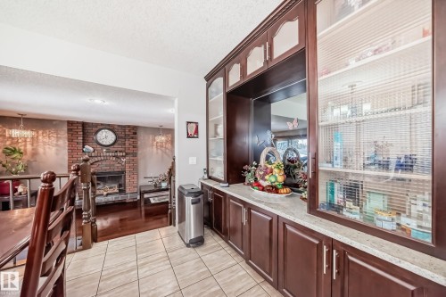 The property features an open floor plan with tiled flooring in the foreground and hardwood flooring visible in the adjacent living area - 12131 101 Street Nw, Edmonton, AB - Indoor With Fireplace