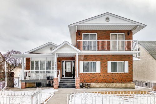 The property features a brick exterior with white trim and a white railing on the porch and upper-level balcony - 12131 101 Street Nw, Edmonton, AB - Outdoor