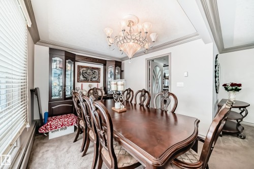 The dining area features a large chandelier, a decorative cabinet with glass doors, and a detailed table with chairs - 12131 101 Street Nw, Edmonton, AB - Indoor Photo Showing Dining Room