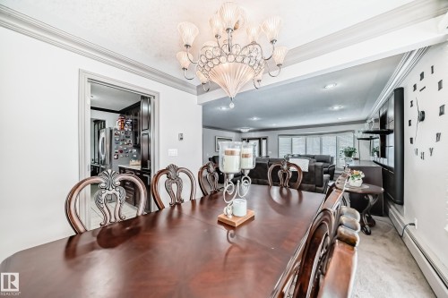 Dining area featuring a dark wood dining table with ornate chairs, an elaborate chandelier, and crown molding - 12131 101 Street Nw, Edmonton, AB - Indoor Photo Showing Dining Room