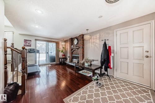 The property features hardwood floors, a brick fireplace, and a sliding glass door leading to the exterior - 12131 101 Street Nw, Edmonton, AB - Indoor With Fireplace