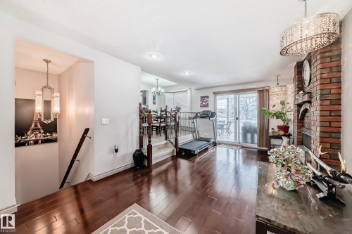The living area features hardwood floors, a brick fireplace, and a sliding glass door leading to the exterior - 12131 101 Street Nw, Edmonton, AB - Indoor