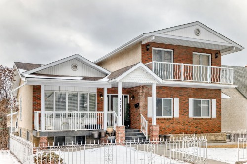 Exterior view of the property featuring a brick and stucco facade, a covered front porch, and a second-story balcony with white railings - 12131 101 Street Nw, Edmonton, AB - Outdoor With Facade