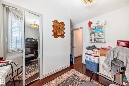 This room features dark hardwood flooring and white walls, with a mirrored closet door providing depth - 12131 101 Street Nw, Edmonton, AB - Indoor