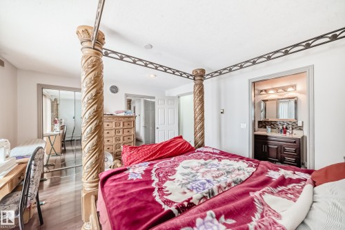 Bedroom featuring light-toned walls and wood flooring, with a partial view of a bathroom vanity and mirror - 12131 101 Street Nw, Edmonton, AB - Indoor Photo Showing Bedroom