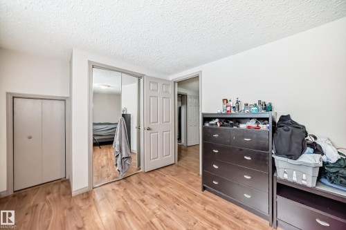 This room features a neutral color palette, hardwood style flooring, a closet with bi-fold doors, and a closet with mirrored sliding doors - 12131 101 Street Nw, Edmonton, AB - Indoor