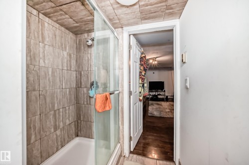 The bathroom features a shower with glass doors and full-height tile surround - 12131 101 Street Nw, Edmonton, AB - Indoor Photo Showing Bathroom