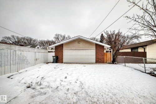 Detached garage with brick and stucco exterior, featuring a white garage door and a side fence - 12131 101 Street Nw, Edmonton, AB - Outdoor With Exterior