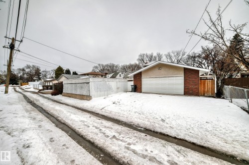 The property features a garage with a white overhead door and brick siding - 12131 101 Street Nw, Edmonton, AB - Outdoor