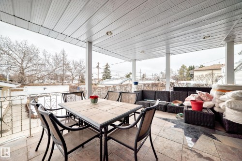 The property features a covered patio with a tile floor and a decorative metal railing - 12131 101 Street Nw, Edmonton, AB - Outdoor With Deck Patio Veranda With Exterior