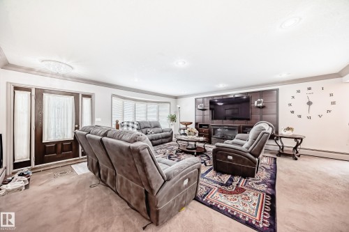 Living room featuring carpeted floors, a decorative area rug, and a front entry door with sidelight windows - 12131 101 Street Nw, Edmonton, AB - Indoor