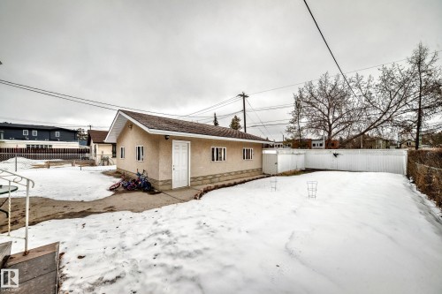 The property features a detached building with a pitched roof and a white exterior door, surrounded by a yard with visible snow cover and a white fence - 12131 101 Street Nw, Edmonton, AB - Outdoor