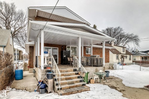 The property features a covered porch with white columns and railings, accessible via stone steps - 12131 101 Street Nw, Edmonton, AB - Outdoor With Facade
