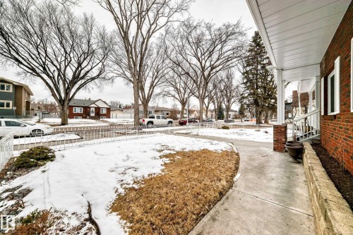 The property features a brick exterior with white shutters, a covered porch with white railing, and a concrete walkway - 12131 101 Street Nw, Edmonton, AB - Outdoor