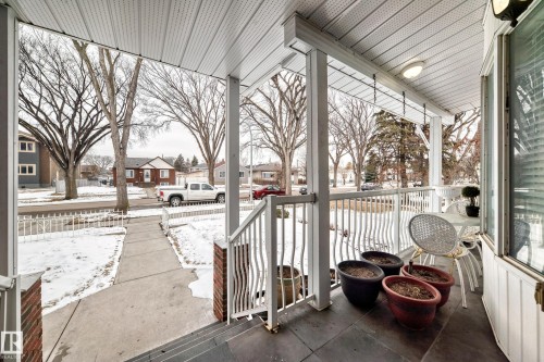Inviting covered front porch with a white railing, brick accents, and a light fixture - 12131 101 Street Nw, Edmonton, AB - Outdoor