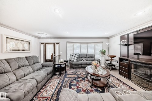 Spacious living area featuring a bay window with blinds, recessed lighting, and a front entry door with side lites - 12131 101 Street Nw, Edmonton, AB - Indoor Photo Showing Living Room