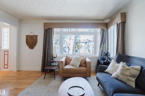 Living area featuring hardwood floors, a large window providing ample natural light, and decorative wall art - 10643 66 Avenue, Edmonton, AB - Indoor Photo Showing Living Room