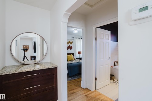This interior view highlights a dark wood cabinet with a light-colored granite countertop, featuring a round mirror above it - 10643 66 Avenue, Edmonton, AB - Indoor