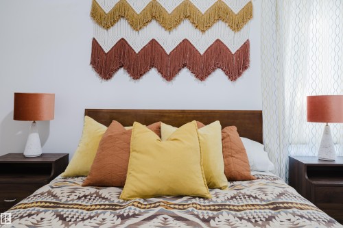 This bedroom features a wooden headboard, two wooden bedside tables, and two table lamps with orange shades - 10643 66 Avenue, Edmonton, AB - Indoor Photo Showing Bedroom